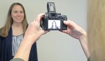 A woman standing against a wall to get a photo taken.