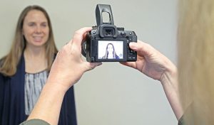 A woman standing against a wall to get a photo taken.