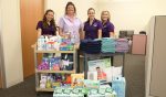 Four domestic relations clerks gather around donated goods in support of Haven of Lake and Sumter Counties.