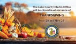 A cornucopia with maize, pumpkins, and apples sits on a picnic table with fall trees in the background and the words "The Lake County Clerk's Office will be closed in observance of Thanksgiving, Nov. 28 and Nov. 29."