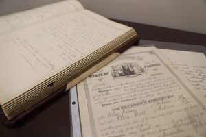 Official record documents laying on a table. One is a historic Marks and Brands book, and the other is the marriage license for Walt Disney's parents.