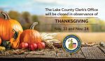 A picnic table in a field with pumpkins, maize, apples and squash on it, and the words "The Lake County Clerk's Office will be closed in observance of Thanksgiving Nov. 23 and Nov. 24."